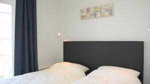 A room with a bed, a window with curtains, and wall art.