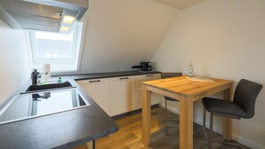 Une cuisine de taille réduite avec une table en bois, un tabouret de bar et une fenêtre.
