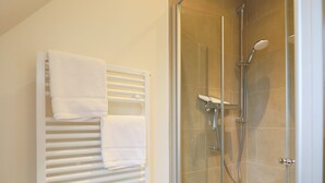 Une salle de bain moderne avec une cabine de douche en verre, un porte-serviettes blanc et une porte de douche en verre.