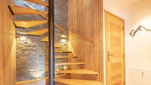 A spiral staircase with wooden steps and a stone wall background. - Luxury chalet for 16 at 150m from cable car in Pra-Loup, sauna, WiFi, non-smoking (Pra-Loup)