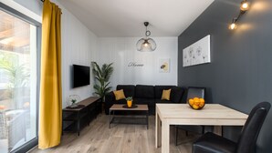 En moderne stue med sofa, sofabord, fjernsyn og spisebord med stole.