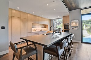 A modern kitchen with a central island, built-in appliances, and a view to the outdoors.