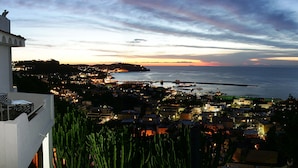 A coastal town at dusk with a view of the sea and a bridge. - Hotel Residence Parco Mare Monte (Casamicciola Terme)