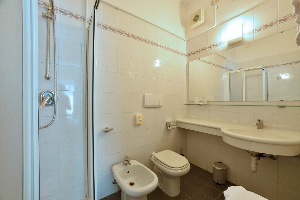 Un baño con ducha, bidé, inodoro, lavamanos y espejo.