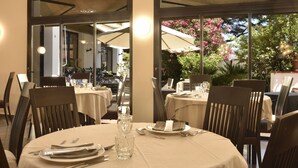 Un restaurante con mesas redondas, sillas y un centro de mesa de vidrio.