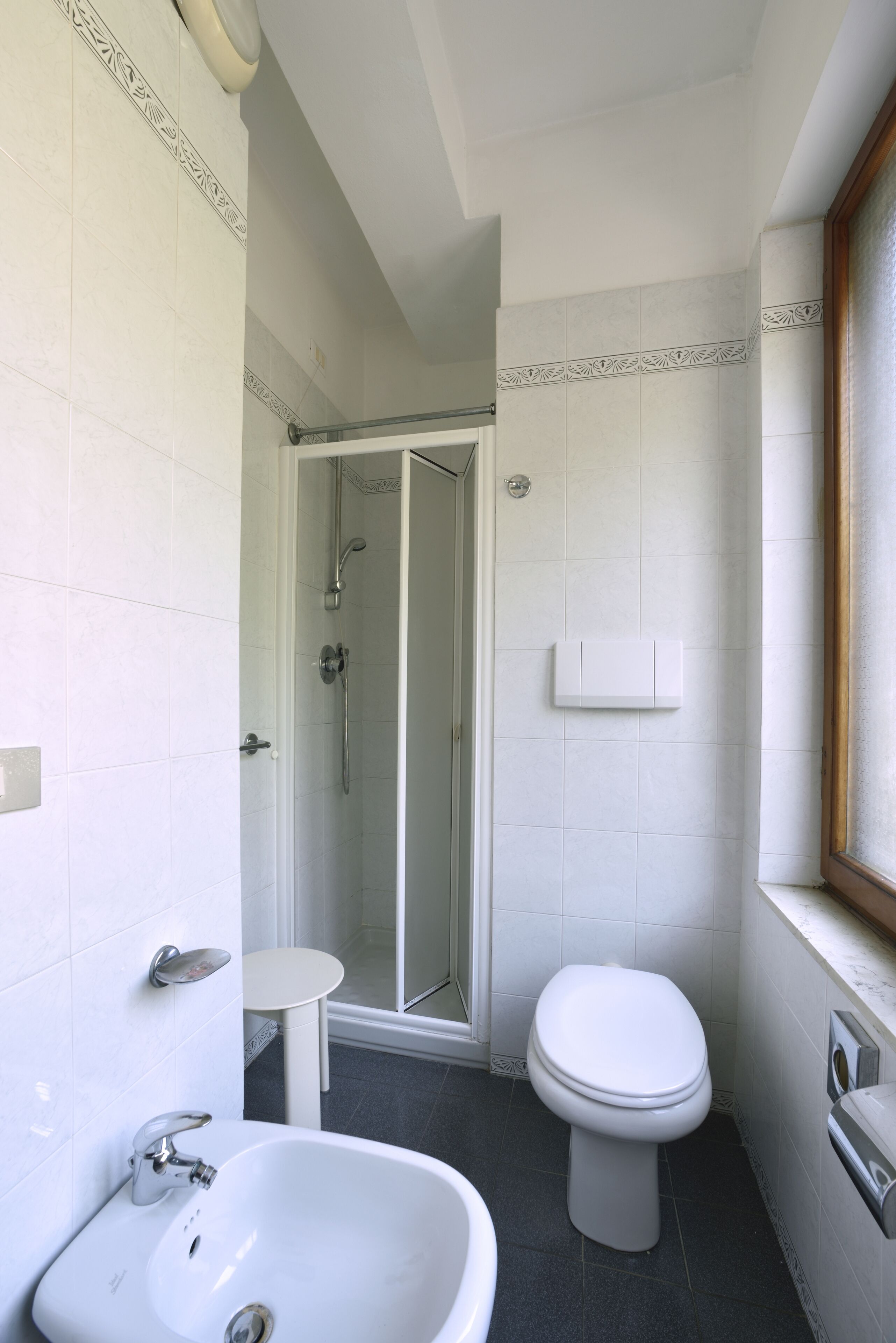 Une salle de bain équipée d’une douche, de toilettes, d’un lavabo et d’une petite table.
