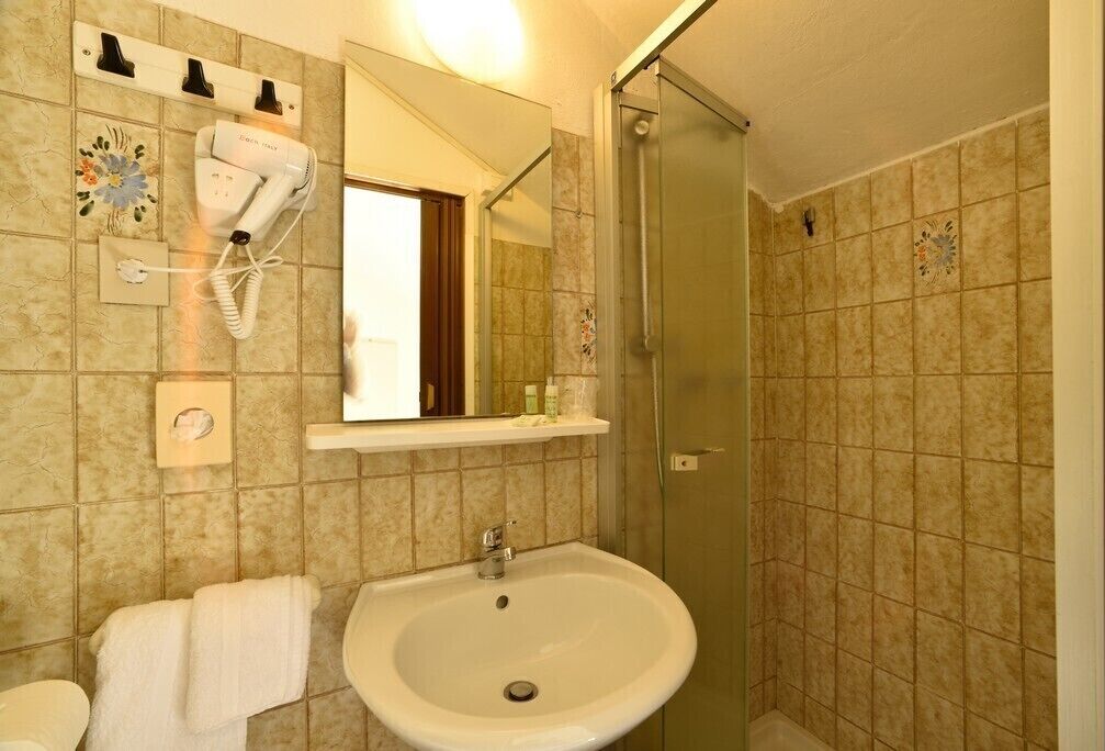 Une salle de bain équipée d’un lavabo, d’un sèche-cheveux et d’une douche.