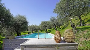 A wooden deck with a pool, surrounded by olive trees and a stone wall. - Villa Gran Paradiso (Toscolano-Maderno)
