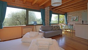 A room with a bed, a sofa, a dining table, and a stone wall.