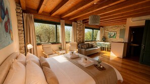 A spacious bedroom with a large bed, a sitting area with a sofa and chairs, and a dining area with a table and chairs. - Villa Gran Paradiso (Toscolano-Maderno)