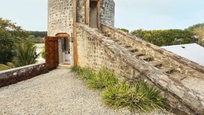 A stone tower with a wooden door and a staircase leading up to it. - Villa (Mahebourg)