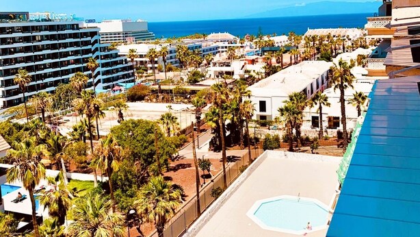 Ein Resort mit Pool, Palmen und Blick auf den Ozean.