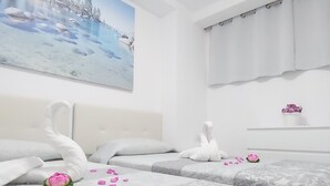 Ein Hotelzimmer mit zwei Betten, einem großen Gemälde an der Wand, einem Fenster mit Vorhängen und einer kleinen Ablage mit einer Blume.