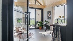 En rummelig stue med højt til loftet, store vinduer og udsigt til det fri.