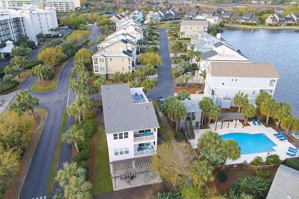 Un quartier résidentiel doté d’une piscine, d’une maison à deux étages avec un balcon et d’une route qui serpente à travers le quartier.