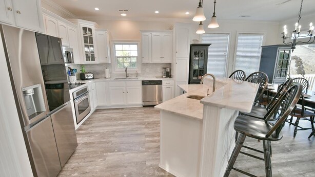 A spacious kitchen with white cabinetry, stainless steel appliances, and a central island.