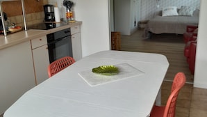 A dining area with a white table, a green decorative bowl, and red chairs.
