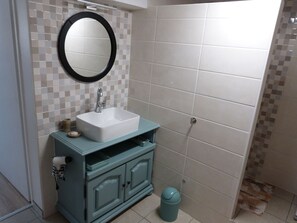 A bathroom with a white sink, a mirror, and a tiled wall.