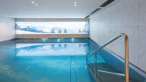 An indoor swimming pool with a view of snow-covered mountains. - New apartment in Megève, wellness access and pool (Megève)