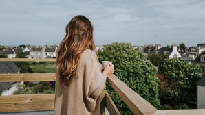 A person standing on a balcony with a view of houses and greenery. - La Brise (Roscoff)