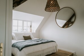 A bedroom with a large bed, a window, a ceiling light, and a round mirror. - La Brise (Roscoff)