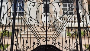 A building with a symmetrical facade, featuring a central entrance with ornate black wrought iron gates. - La Brise (Roscoff)