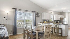 Een moderne keuken met witte kasten, een centraal eiland en een eetgedeelte met een tafel en stoelen.