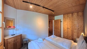 Ein Schlafzimmer mit Holzbalkendecke, einem Bett, einem Nachttisch und einer Lampe.