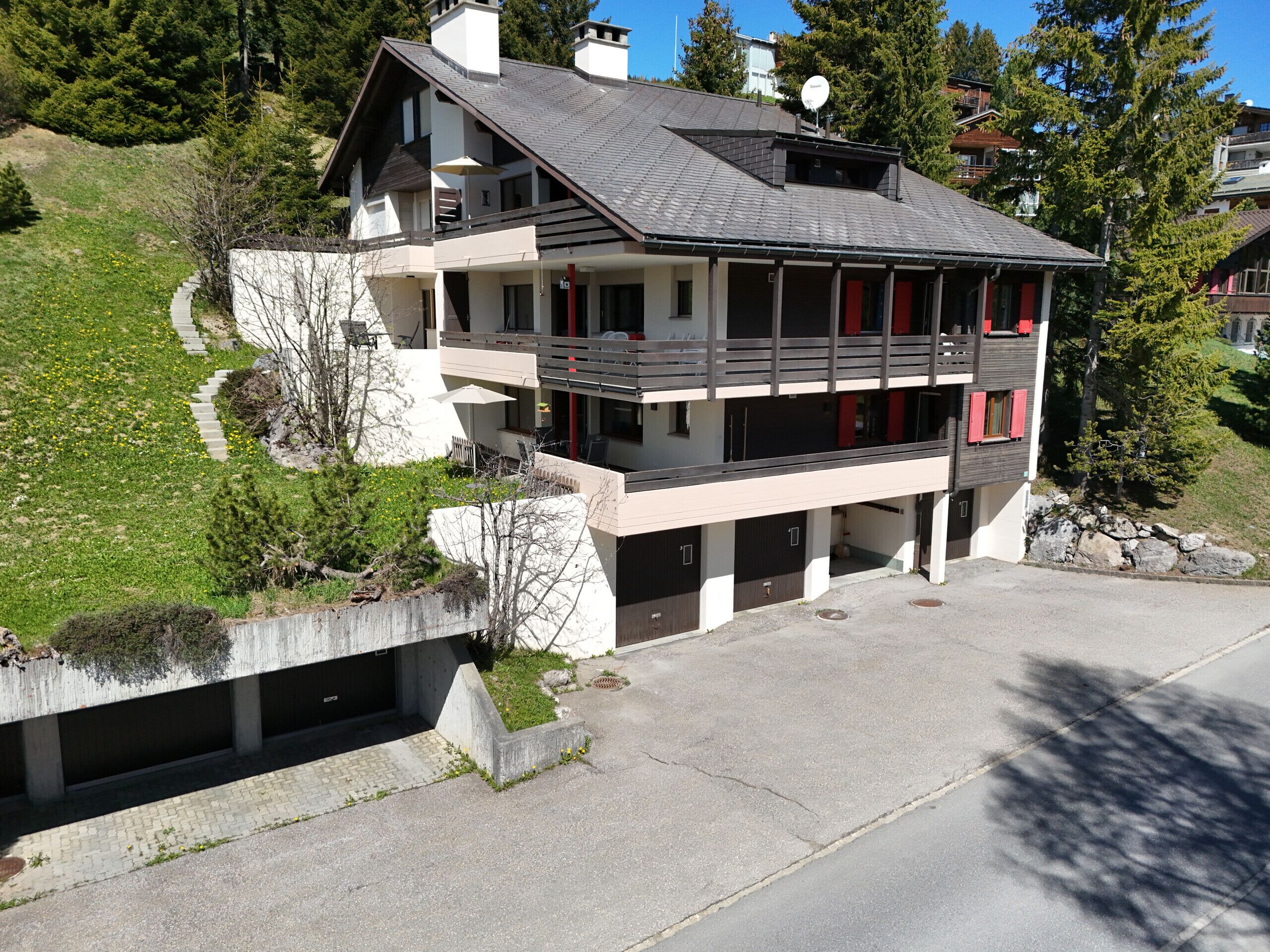 A two-story modern house with a balcony, a garage, and a driveway.