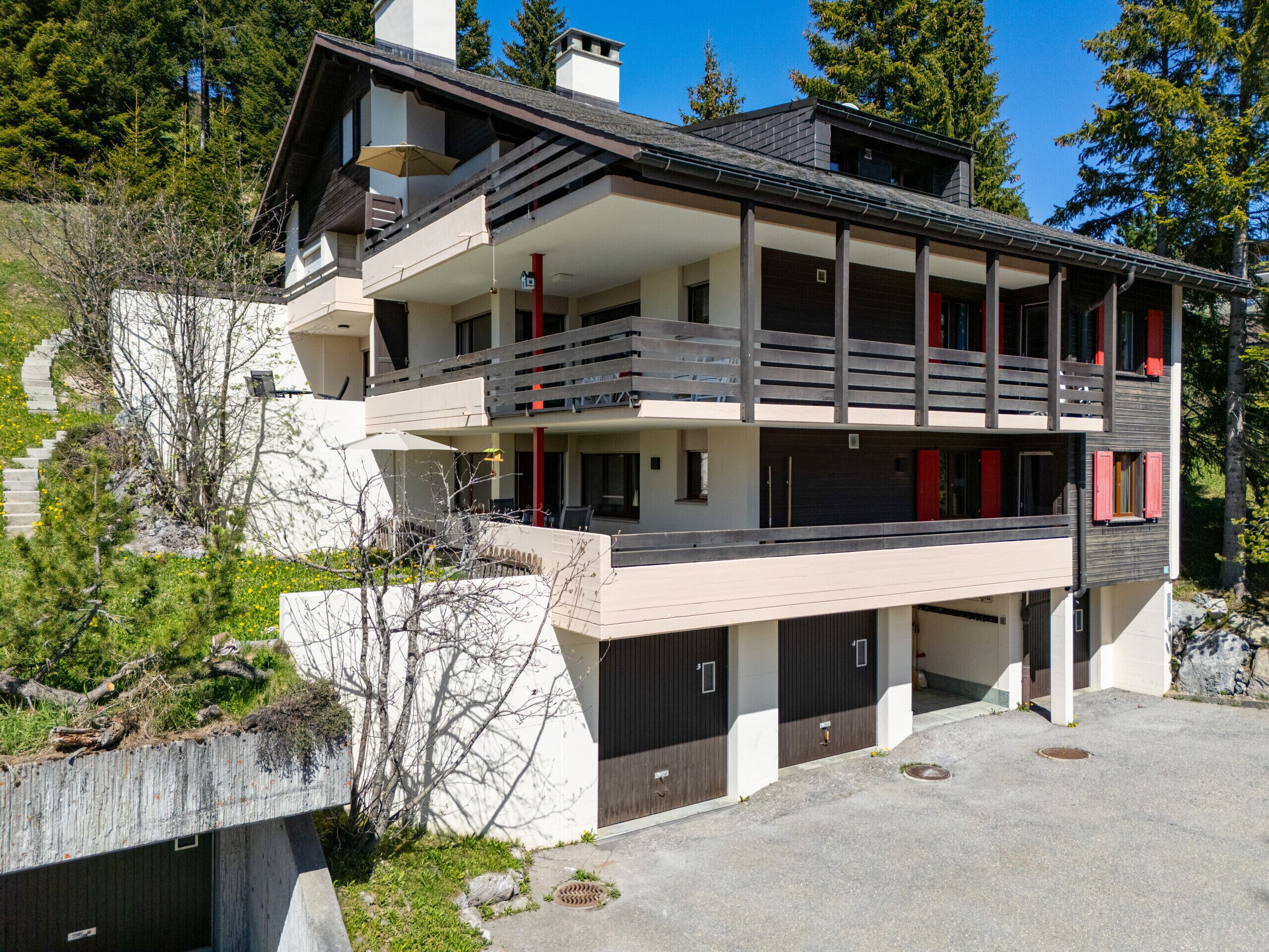 A multi-story building with balconies, a garage, and a staircase leading to a lower level.