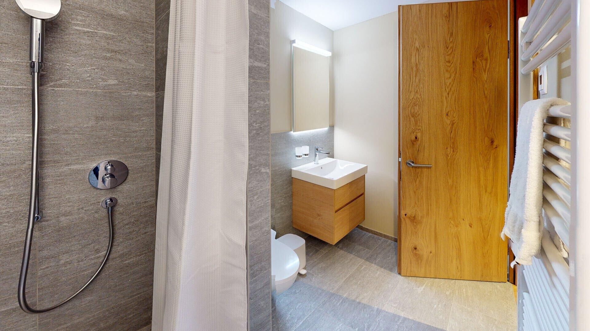 Une salle de bain moderne équipée d’une douche, de toilettes et d’un lavabo.