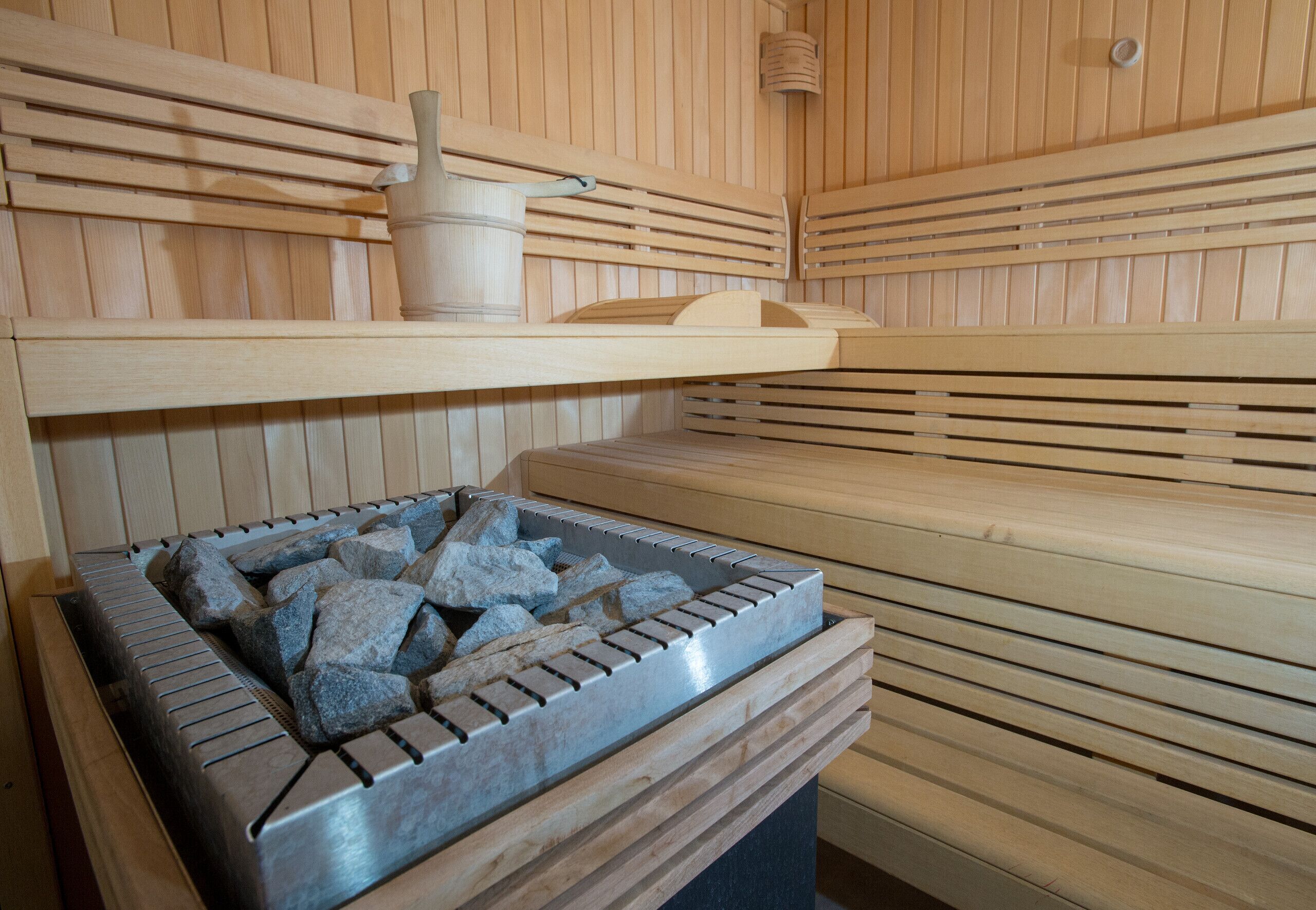 Eine Sauna mit Holzbänken und einem Steinkessel zum Erwärmen der Steine.