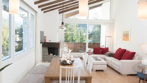 A spacious living area with a wooden dining table, white sofas, and a fireplace. - Attic apartment with pool, sauna, and fireplace (Lenzerheide/Lai)