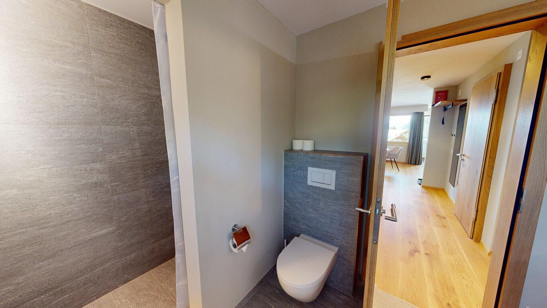 Ein kleines Badezimmer mit Toilette, Seifenspender und einer Ablage für Pflegeprodukte.