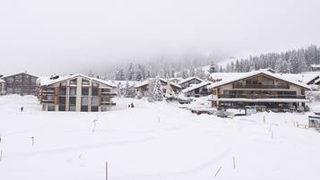 A snow-covered ski resort with chalet-style buildings, a ski lift, and a mountain backdrop.