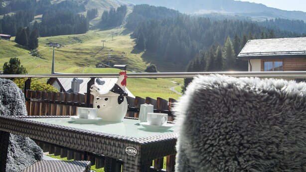A view of a mountainous landscape with a wooden cabin and a table with a teapot and cups. - Ski in-Ski out holiday flat Heimberg in Parpan- Lenzerheide (Parpan)