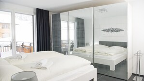 A modern hotel room with a large bed, a glass partition, and a view of the outside. - Ski in-Ski out holiday flat Heimberg in Parpan- Lenzerheide (Parpan)