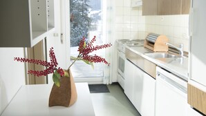 Une cuisine moderne avec des meubles blancs, un évier en acier inoxydable et une planche à découper en bois.