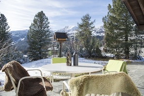 A round table with chairs, a bird feeder, and a vase.