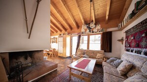 A cozy living room with a fireplace, wooden furniture, and a large window.