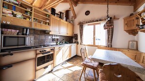 A kitchen with wooden cabinets, a stove, and a dining area with a table and chairs.