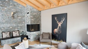 Una sala de estar acogedora con chimenea de piedra, un cuadro grande de un ciervo y muebles modernos.