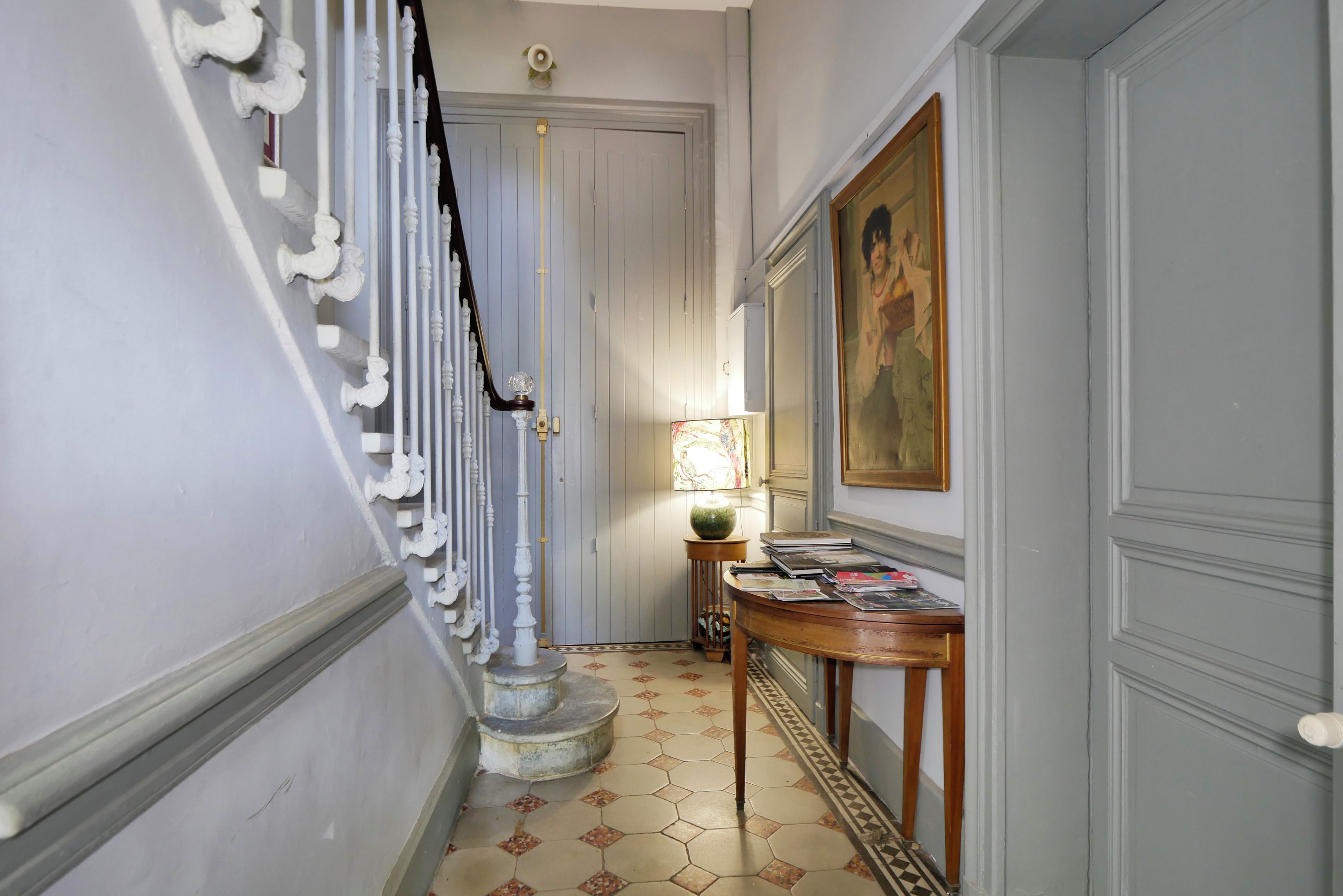 Un pasillo con una escalera, una mesa con revistas y un cuadro en la pared.