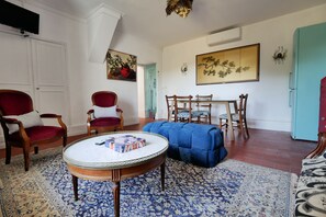 A living room with a round coffee table, two armchairs, a sofa, a dining table with chairs, and a refrigerator. - 2-Star Apartment in a Writer's Home (Sommières)