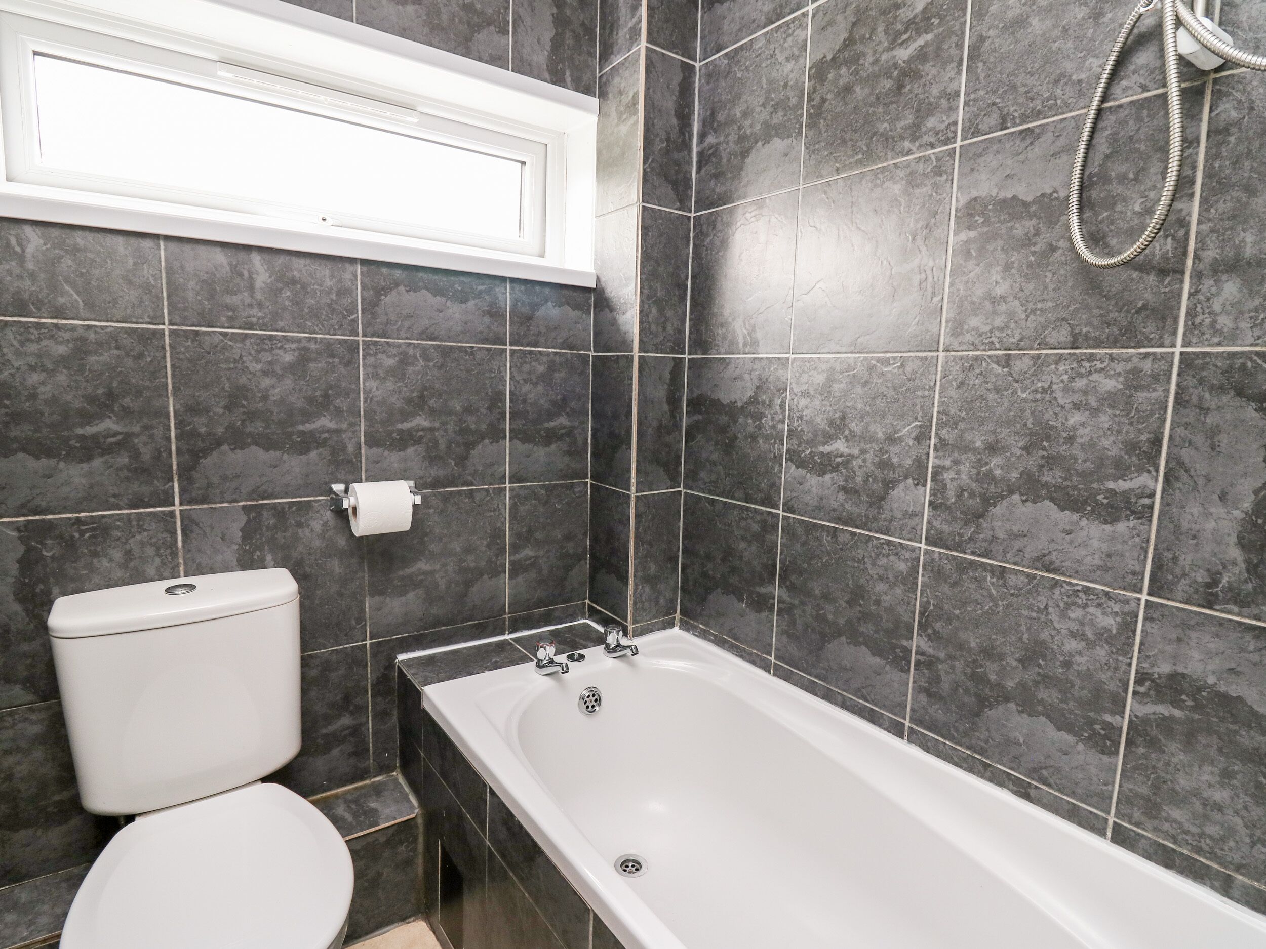Een badkamer met toilet, bad en douche.