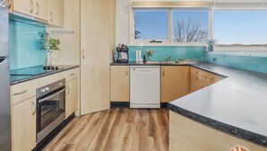 Eine moderne Küche mit Holzausstattung, einem Geschirrspüler und einem Fenster mit Blick auf die Landschaft.