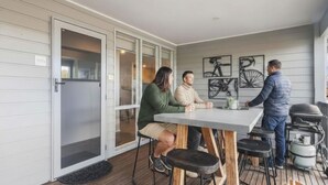 Eine überdachte Terrasse mit Tisch und Stühlen, eine Glastür zum Verschieben und eine Wand mit Fahrradmotiven.