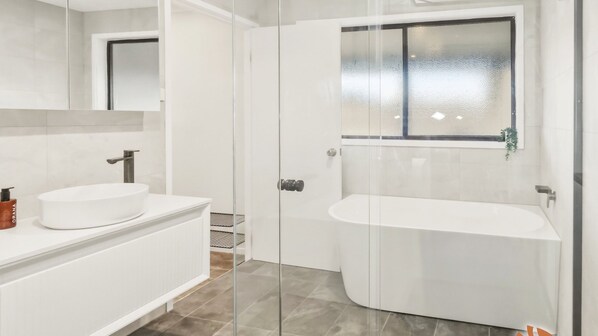 Ein modernes Badezimmer mit Duschkabine aus Glas, einem weißen Waschbecken und einer freistehenden Badewanne.