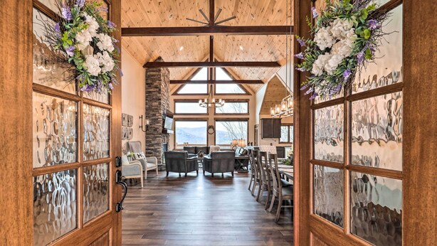 A spacious room with a wooden floor, large windows, and a stone wall. - Mountainside Family Retreat w/ Deck in Banner Elk! (Banner Elk)