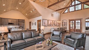 A spacious living room with a high ceiling, leather sofas, a wooden coffee table, and a dining area with chairs. - Mountainside Family Retreat w/ Deck in Banner Elk! (Banner Elk)